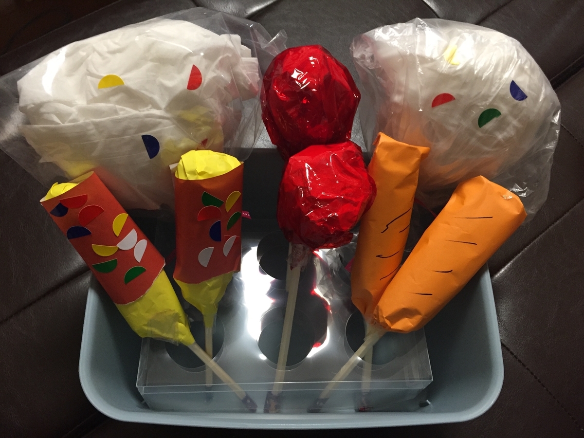 屋台屋さんごっこ②﻿ 『りんご飴屋さん』﻿ りんご飴は、新聞紙を丸めて割り箸をさして 土台を作ります。※赤のビニールテープで割りばりの部分を固定しました。﻿﻿ その後、子ども達が赤の折り紙で新聞紙を包み、のりづけをします。﻿ ←りんご完成﻿ そして赤のセロハンを